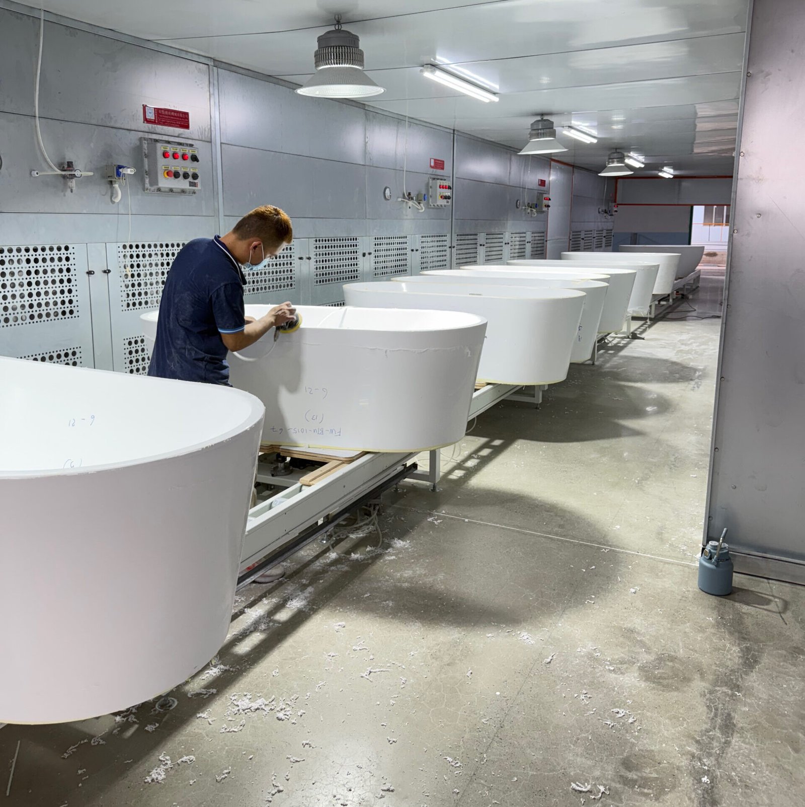 Worker processing an acrylic bathtub on the production line